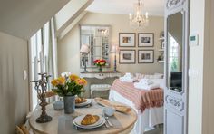 a room with a table, chairs and pictures on the wall above it that has flowers in vases