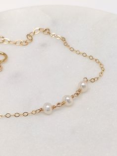 "Our gift to you 10% off your first purchase. Details here - http:/eepurl.com/dpVPBz The perfect pearl bracelet. One, two or three dainty pearls are suspended on our signature chain. Perfect for that special occasion yet simple enough for everyday wear. Layer them together or with other favorites DETAILS 14 k fill or Sterling Silver. Pearls are approximately 3 mm. Each freshwater pearl is unique meaning the size and shape may vary slightly. Comes with a 1\" extender chain to fine tune your fit. Simple Gold Bracelet, Gold Bracelet Simple, Wishbone Necklace, Unique Meaning, Minimal Gold, Dot Necklace, Single Pearl, Bracelet Simple, One Two Three