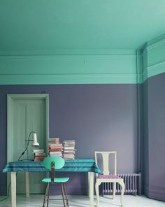 a room with two chairs and a table covered in books on top of the floor