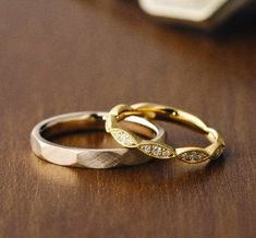 two wedding rings sitting on top of a wooden table