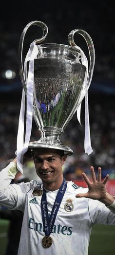 the soccer player is holding his trophy on top of his head and smiling at the camera