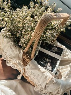 a basket with flowers in it sitting on top of a bed next to a pillow