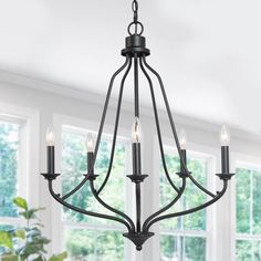 a black chandelier with five lights hanging from it's centerpiece in a dining room