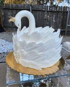 a white swan cake sitting on top of a glass table covered in frosting and icing