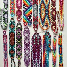 many colorful bracelets are lined up on a white surface and one is in the middle