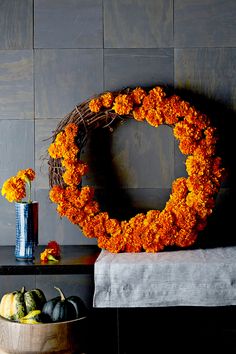 an orange wreath sits on a table next to some pumpkins