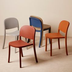 four different colored chairs sitting next to each other in a room with white walls and flooring