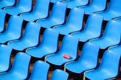 rows of blue plastic chairs with one empty bottle in the middle, sitting side by side