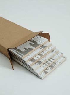 a stack of books sitting inside of a cardboard box on top of a white table