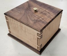 a wooden box sitting on top of a white floor next to a button in it