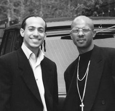 two men standing next to each other in front of a car