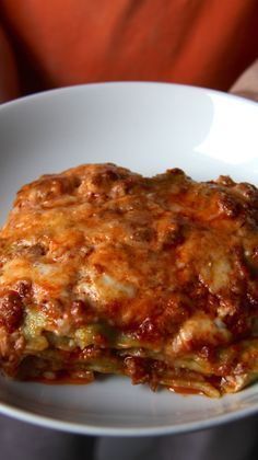 a white plate topped with lasagna covered in sauce