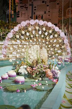 an elaborate flower arrangement on display in a room with water lilies and cupcakes