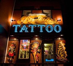 the front of a tattoo shop lit up at night