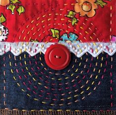 a red button sitting on top of a patchwork piece of cloth with floral designs