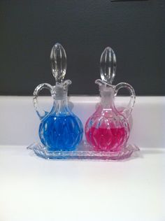 two colorful glass vases sitting on top of a white counter next to each other