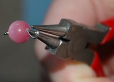 a person is holding a tiny object in their right hand and it has a pink bead on the end