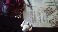 an old piece of paper with buttons and scissors on it next to a doll's hand