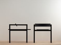 two black chairs sitting next to each other in front of a white wall and floor