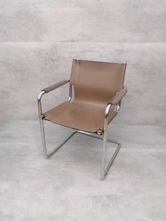 a brown leather chair sitting on top of a cement floor next to a white wall