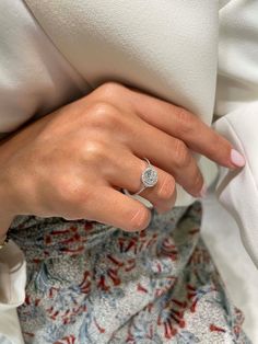 a close up of a person's hand with a ring on their finger and wearing a white shirt