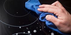 a person cleaning an electric stove with a blue cloth on it's burner