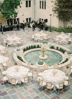 tables and chairs are arranged around a fountain in the middle of an outdoor courtyard area