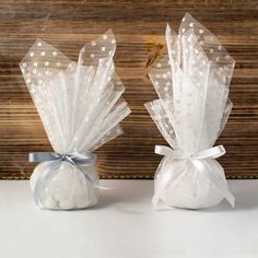 two white bags filled with cotton balls on top of a wooden table next to each other