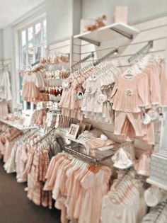 baby clothes on display in a store with pink and white ones hanging from the ceiling