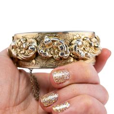 Embrace the timeless elegance of of the 1950s with this exquisite Marino gold cuff. Crafted with meticulous attention to detail, this vintage statement piece features intricate floral repoussé. With this mid-century glamor piece, you'll have the perfect accessory for retro inspired ensembles or a unique addition to any jewelry box.   The piece is signed Marino and is good vintage condition. There are flowers in repousse held by trailing banners. There are etchings of flowers patterning the brace Vintage Yellow Gold Cuff Bracelet With Intricate Design, Formal Cuff Bracelet With Intricate Design, Heirloom Cuff Bracelet With Intricate Design For Formal Occasions, Antique Cuff Bracelet For Formal Occasions, Elegant Gold Bracelets For Vintage Events, Vintage Gold Cuff Jewelry, Vintage Yellow Gold Cuff Bracelet For Ceremonial Occasions, Antique Hinged Cuff Bracelet For Formal Occasions, Vintage Engraved Cuff Bracelet For Formal Events