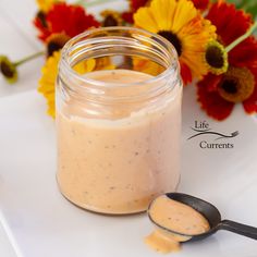 a jar filled with food sitting next to a spoon on top of a white plate