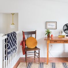 a room with a desk, chair and fan