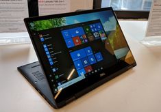 an open laptop computer sitting on top of a white table next to windows 10 and 8