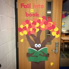 a door decorated to look like a tree with leaves on it and the words fall into a book