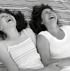 two women laying in bed with their mouths open