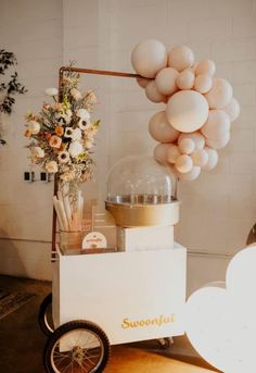 a cart with some balloons on top of it and a vase filled with flowers in the back