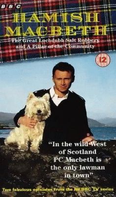 a man holding a white dog on top of a rocky cliff next to the ocean