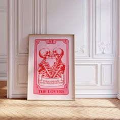 a red and white poster sitting on top of a wooden floor next to a wall