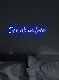 there is a neon sign that says drunk in love on the wall above a bed