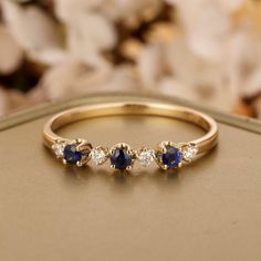 three diamond and sapphire ring in yellow gold with white diamonds on the side, sitting on a table