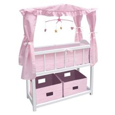 a baby crib with pink curtains and two baskets under the canopy, on top of a white shelf