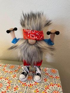 a stuffed animal is sitting on top of a table with two dumbbells in it's hands