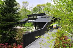 a black house surrounded by trees and flowers