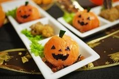 two white plates topped with small pumpkins on top of a black table covered in food