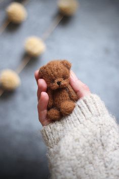 a person holding a small teddy bear in their hand