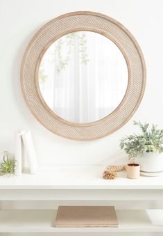 a white table topped with a round mirror and potted plant on top of it