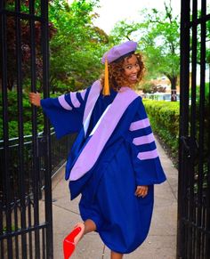 a woman in a blue graduation gown and red shoes