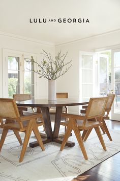 a dining table with chairs around it and a vase on the table next to it