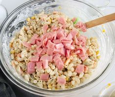 ham and macaroni salad in a glass bowl with a wooden utensil