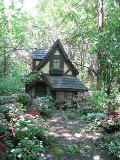 a small house in the woods surrounded by flowers